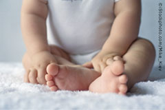 Baby seated on white fabric.